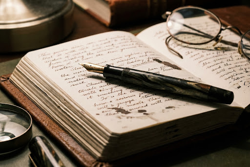 A vintage fountain pen resting on a leather-bound journal